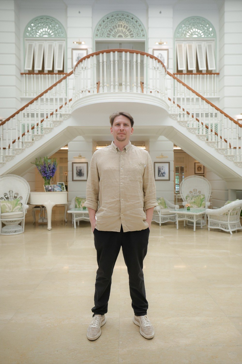 Felix Krüger standing in a bright hotel lobby with a curved staircase