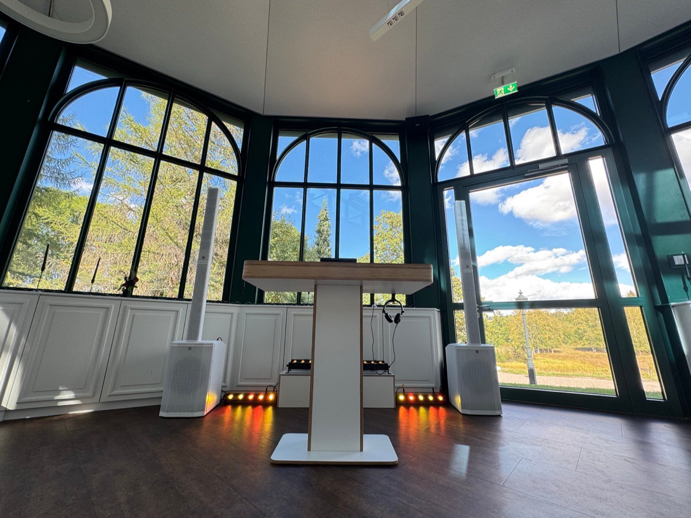 DJ-Tisch in Weiß und Holz mit weißen Lautsprechern im verglasten Pavillon des Parkhotel Adler