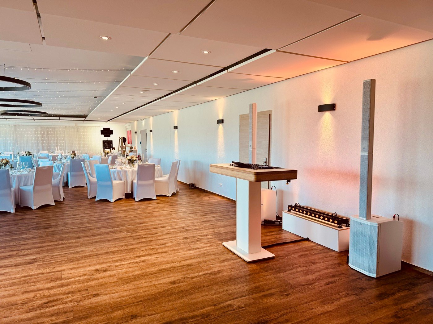Mein DJ-Tisch in Weiß und Holz im Saal der Reblaus, im Hintergrund festlich gedeckte Tische